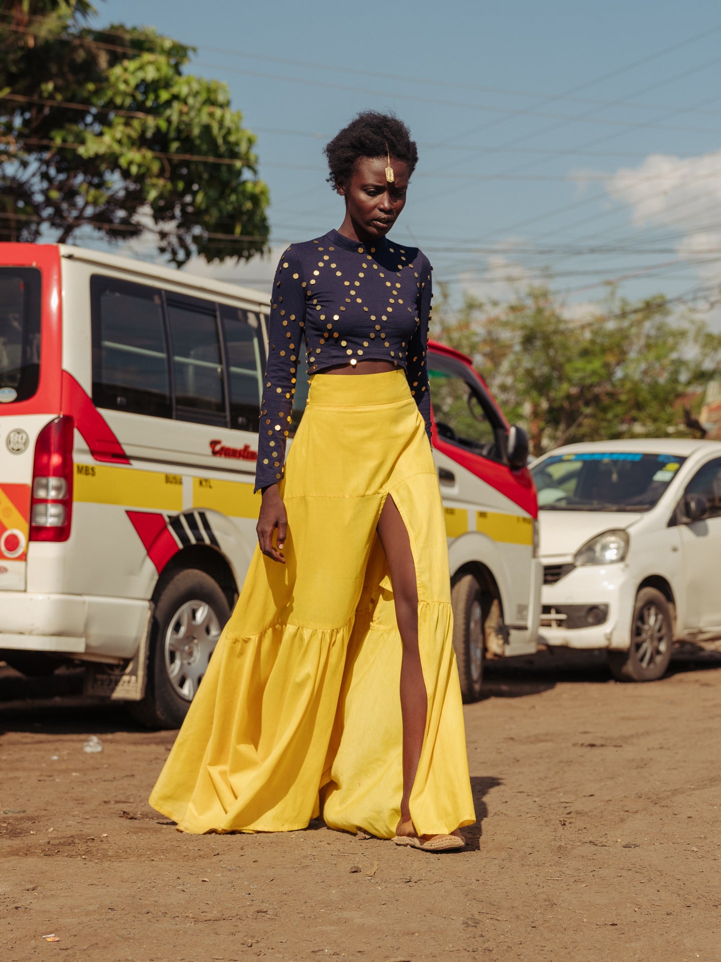 Model walking in bright yellow tiered cotton maxi skirt with thigh-high slit