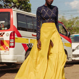 Model walking in bright yellow tiered cotton maxi skirt with thigh-high slit