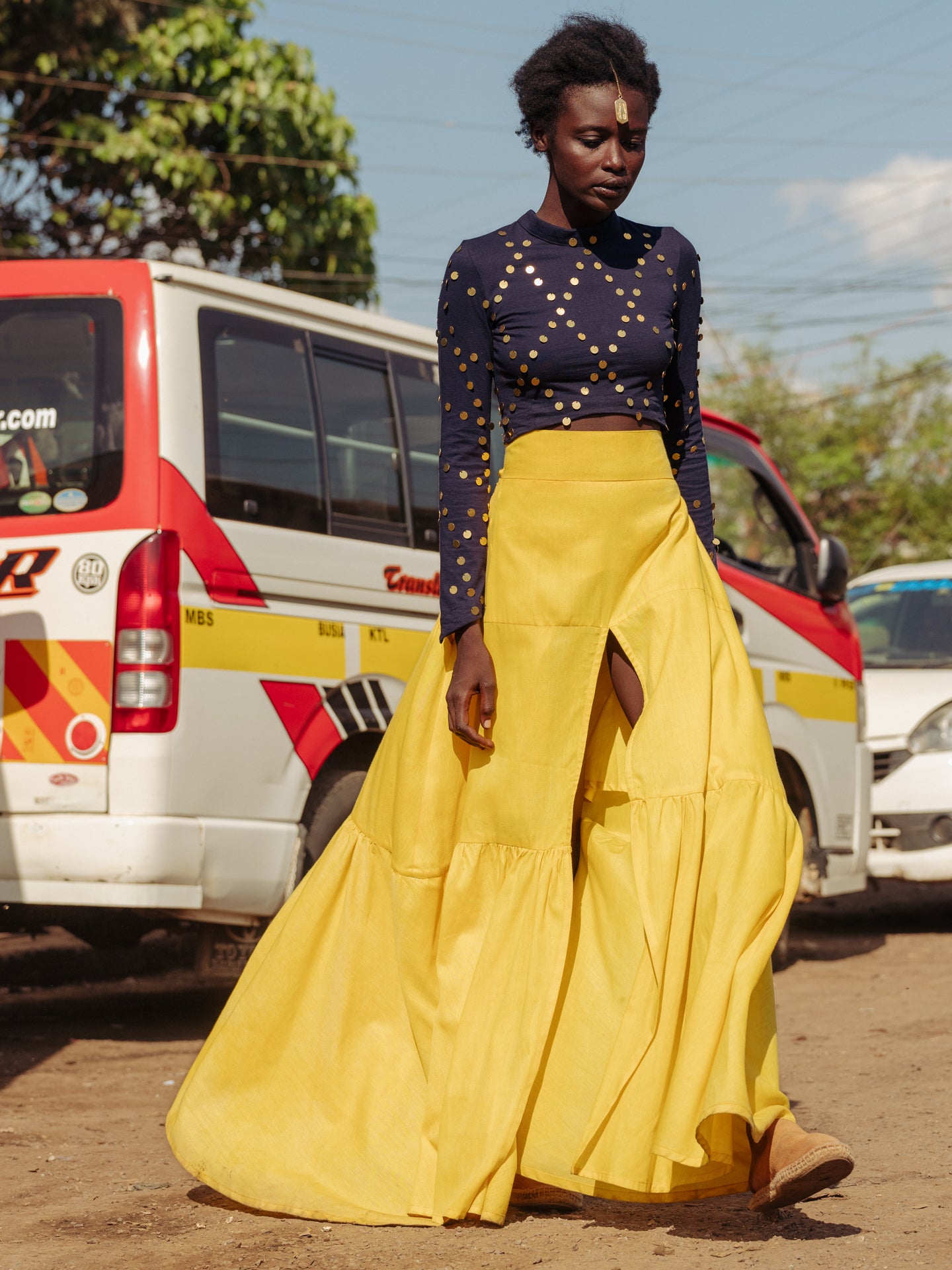 Model walking in bright yellow tiered cotton maxi skirt with thigh-high slit