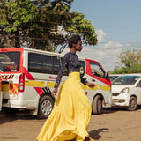 Model walking in bright yellow tiered cotton maxi skirt with thigh-high slit