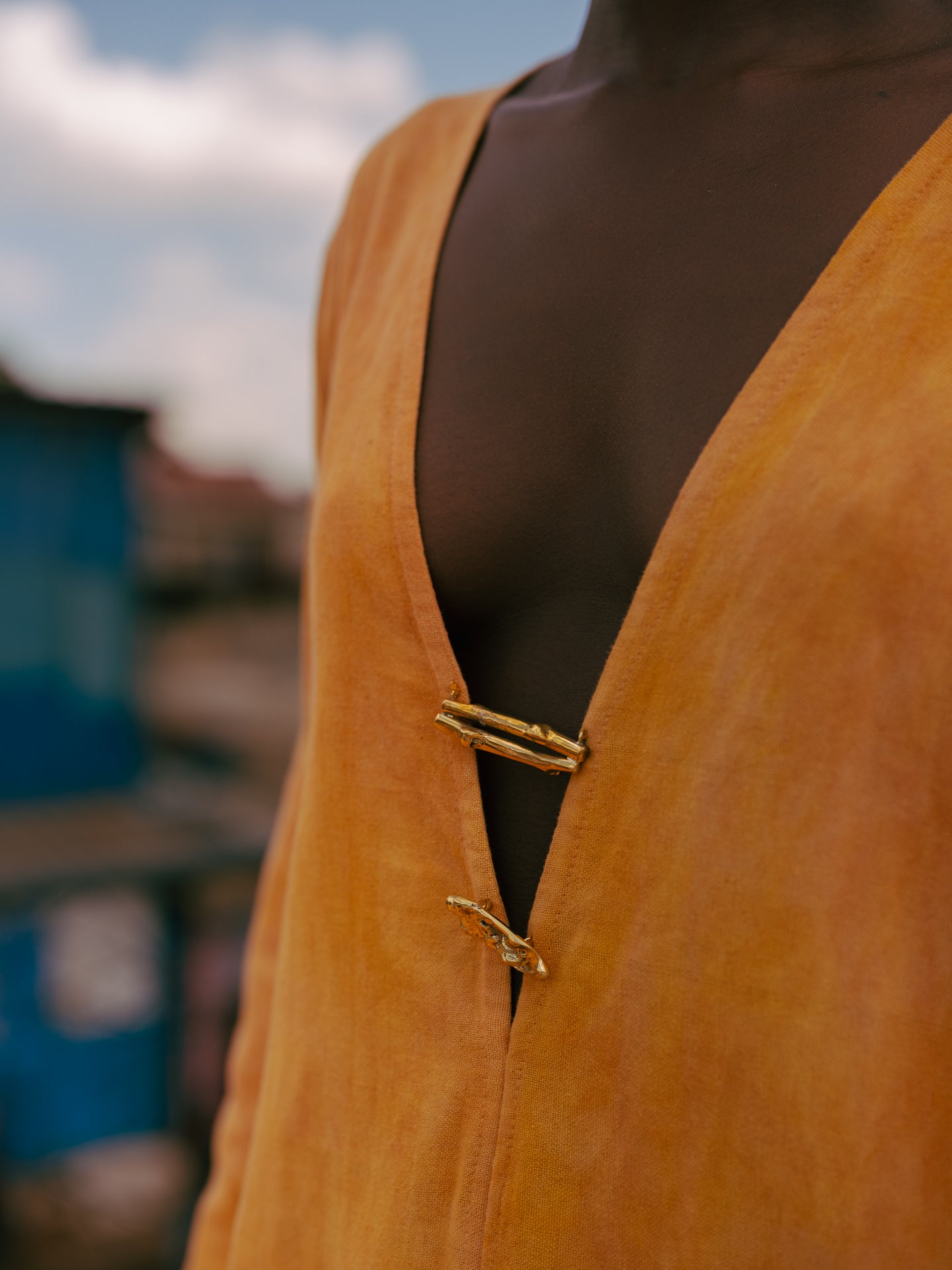 Artisan hand-cast brass hardware and turmeric-dyed cotton fabric on LilaBare kaftan tunic