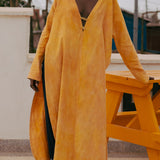 Model wearing LilaBare’s plunge kaftan tunic, hand-dyed with turmeric and red soil, featuring brass closures and waist-level slits