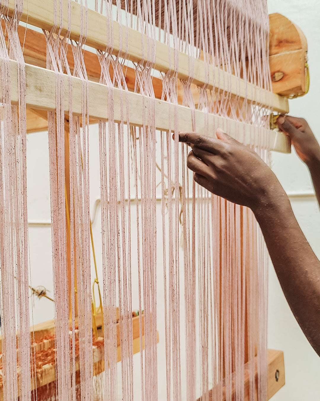 closeup of artisan hands on wooden loom making LilaBare signature cotton weave