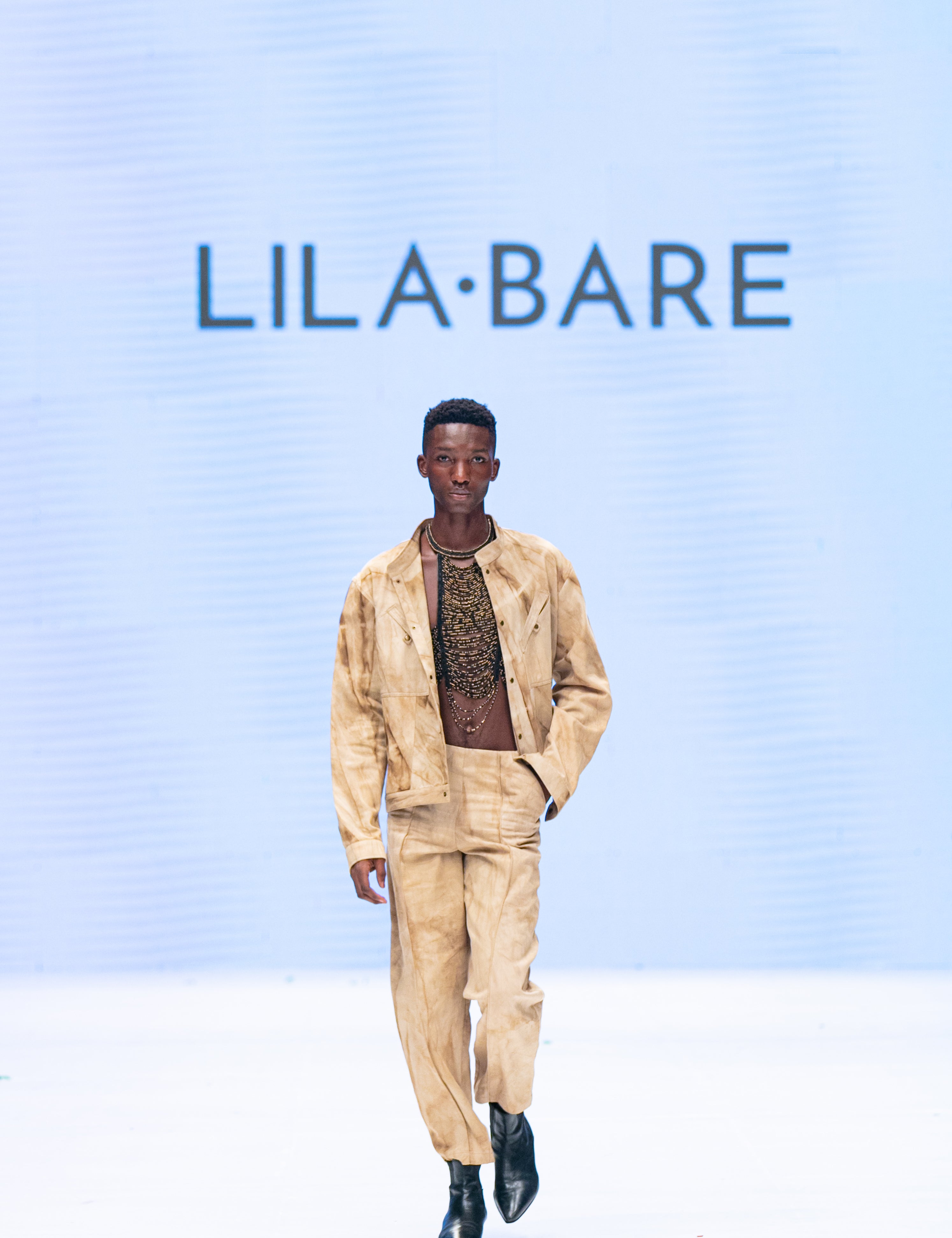Model wearing marbled safari jacket in natural ochre tie-dye on runway