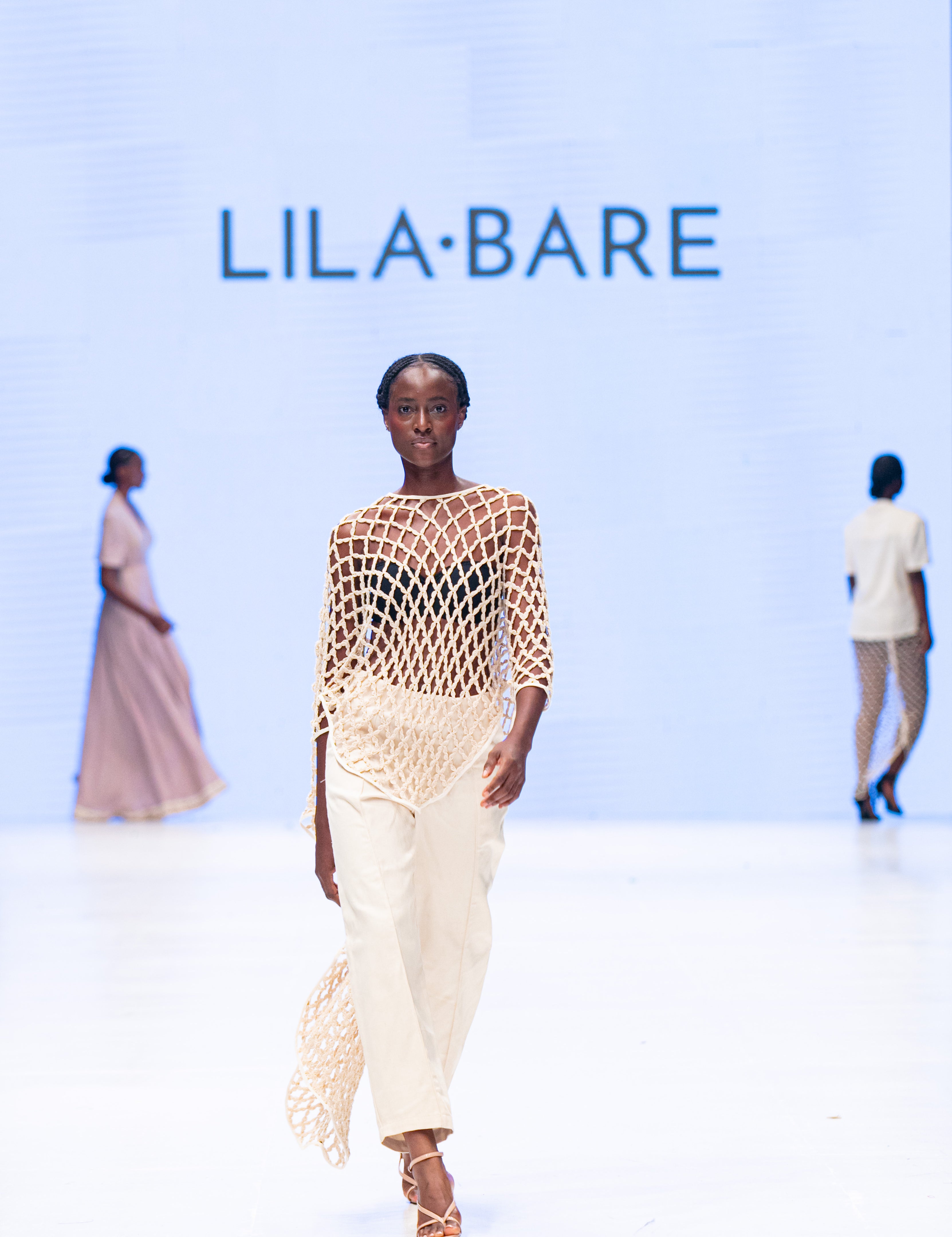 Runway LilaBare model wearing hand-crocheted cotton bolero mid-movement, capturing fishnet crochet and fluid silhouette