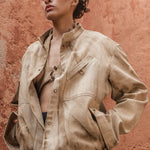 Model wearing marbled safari jacket in natural red-soil tie-dye against a terracotta wall