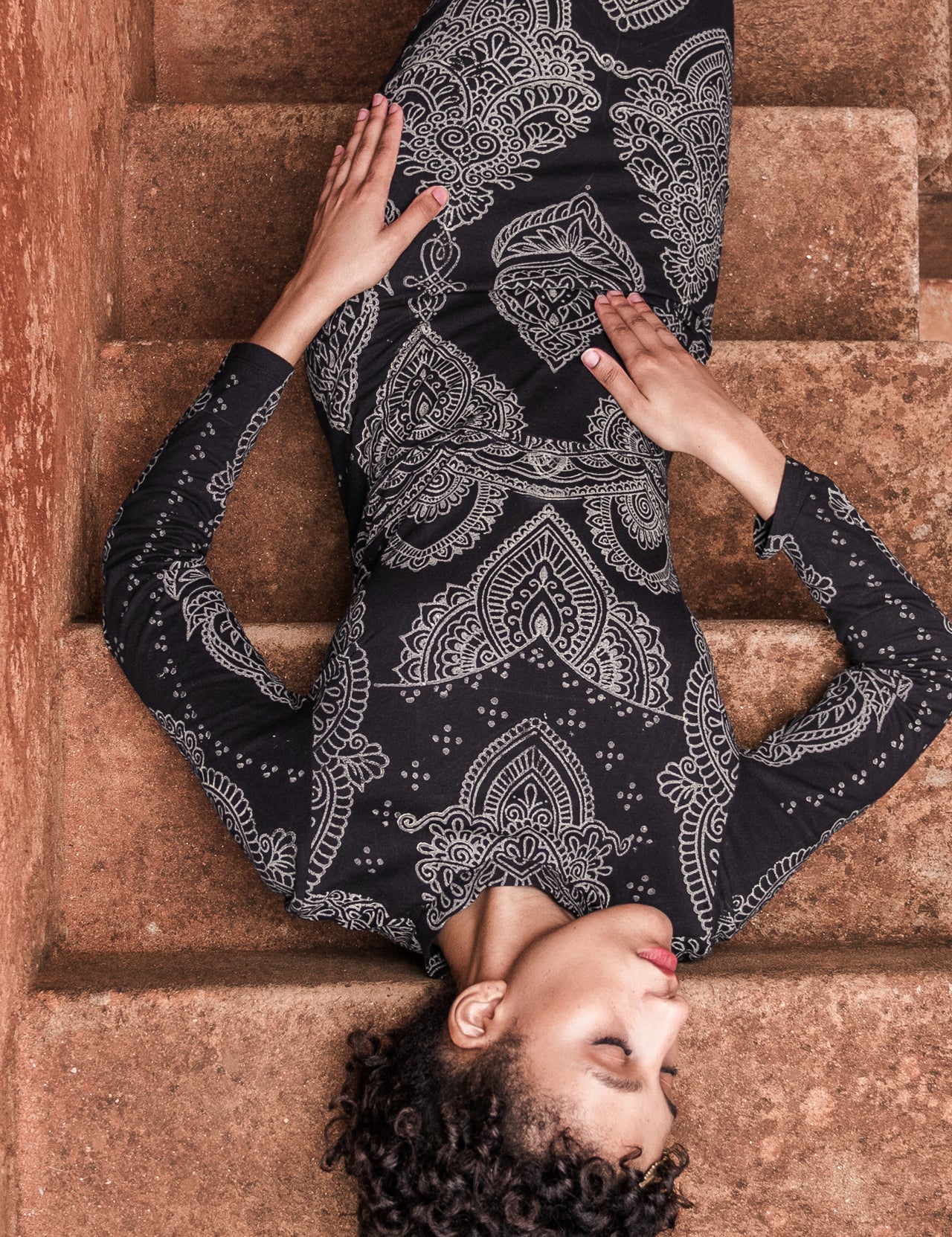 Clos up of model in black form-fitting Mehendi Cocktail Dress with long sleeves, featuring digitally engineered laser-engraved blockprint design in natural cotton jersey by LilaBare.