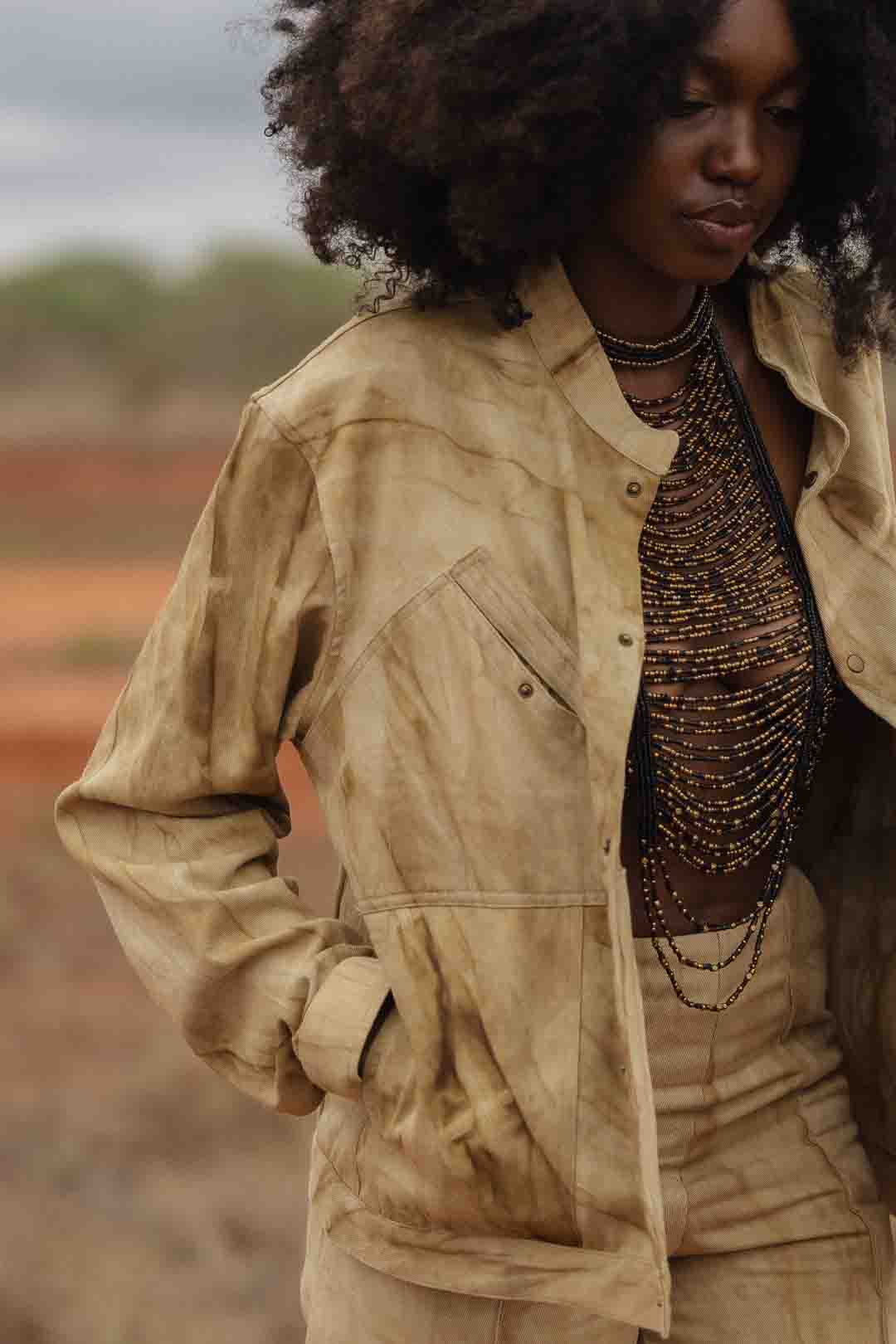 Closeup of handmade luxury leather and bead halter by LilaBare styled with jacket on model in nature