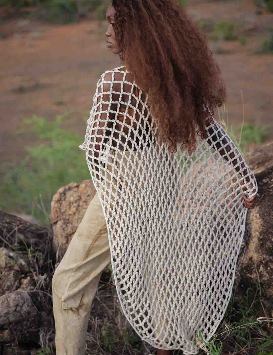 Back view of LilaBare model wearing hand-crocheted cotton bolero mid-movement, capturing fishnet crochet and fluid silhouette