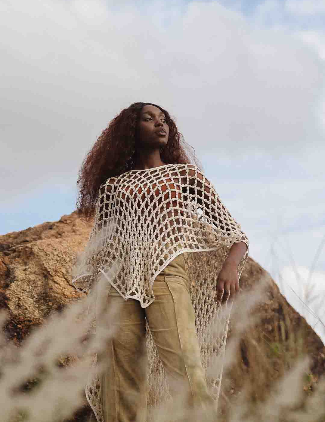 Full length view of LilaBare model wearing hand-crocheted cotton bolero mid-movement, capturing fishnet crochet and fluid silhouette