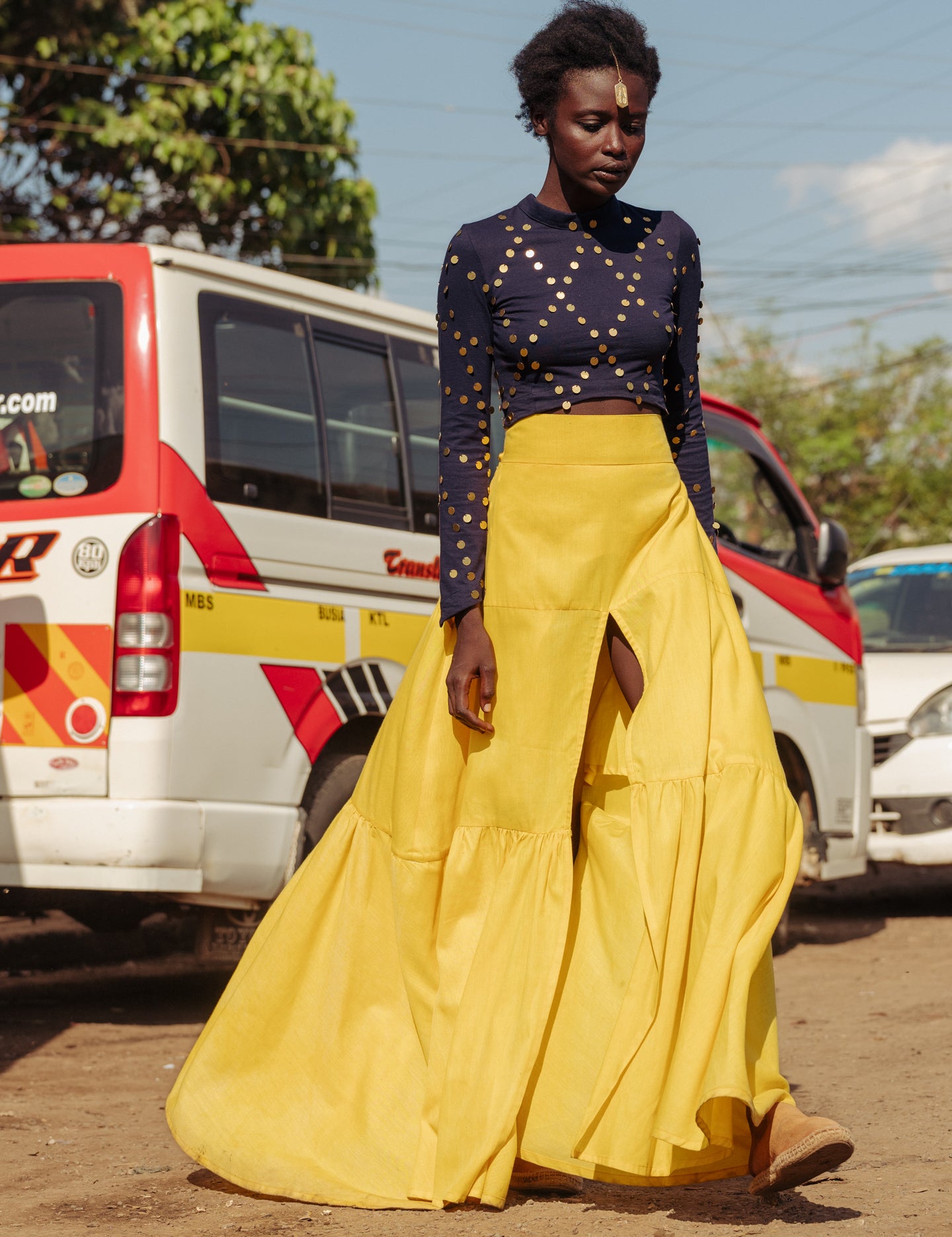 Model walking in bright yellow tiered cotton maxi skirt with thigh-high slit