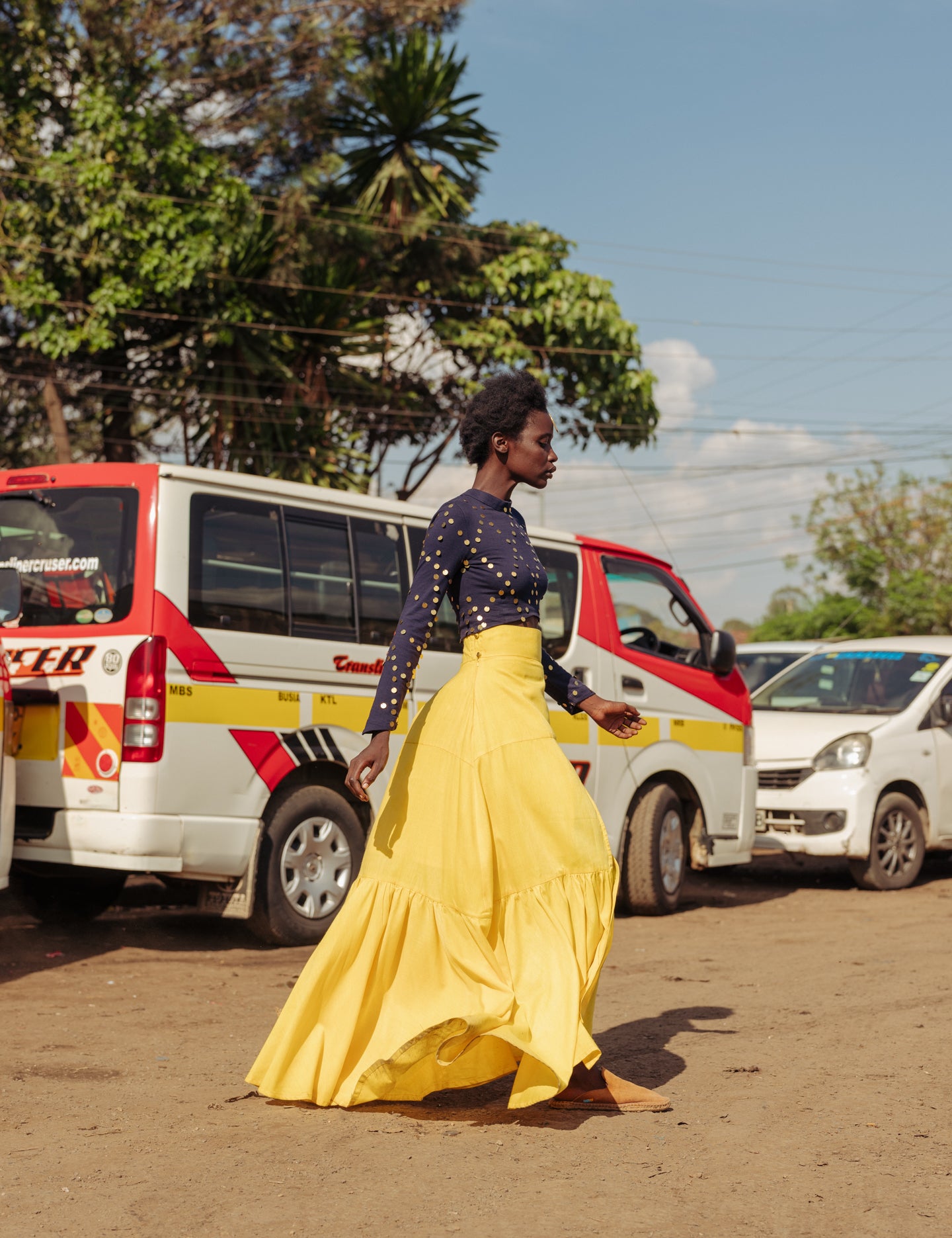 Model walking in bright yellow tiered cotton maxi skirt with thigh-high slit