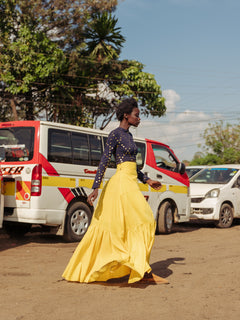 Model walking in bright yellow tiered cotton maxi skirt with thigh-high slit