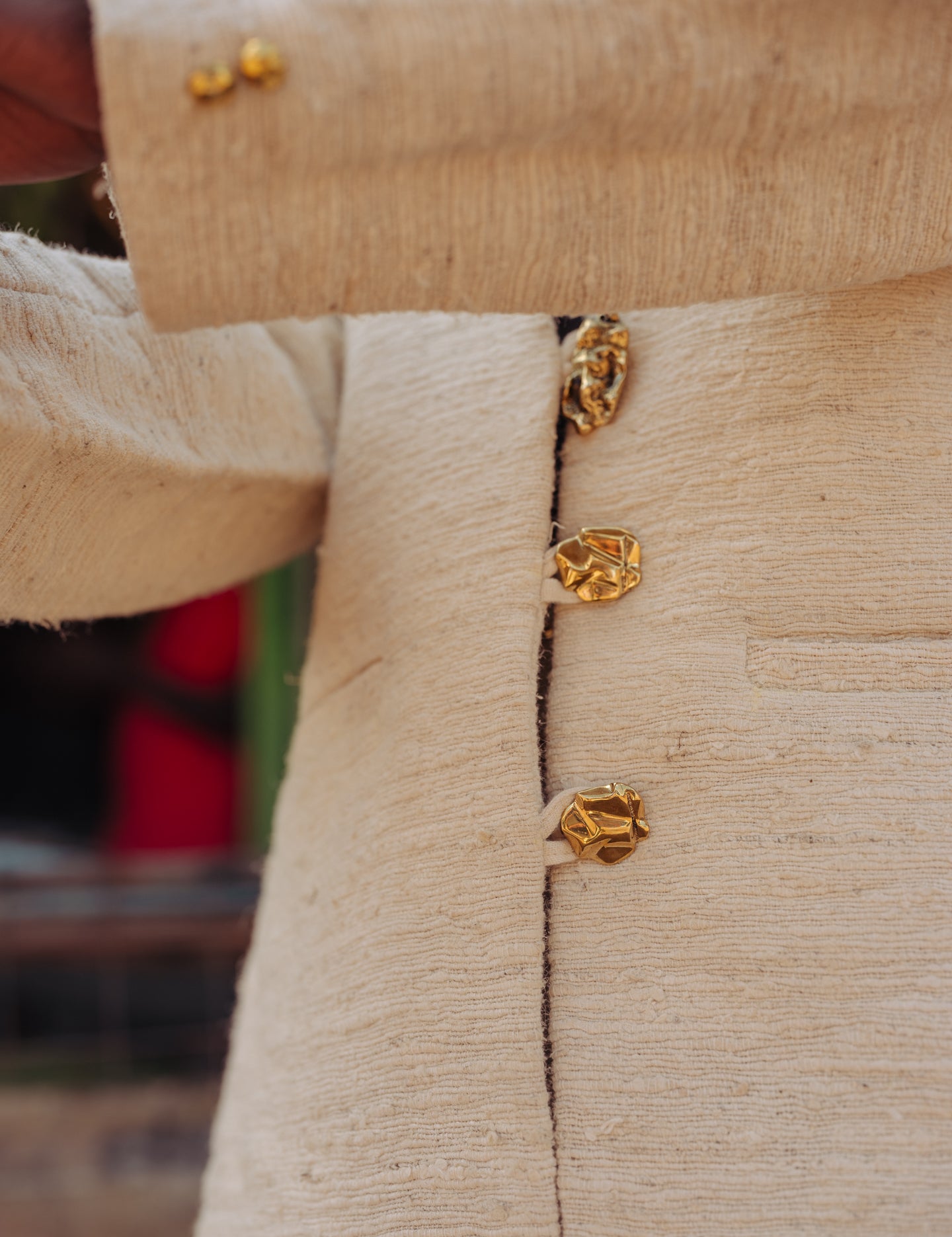 Close-up of handwoven pineapple fiber fabric and brass buttons of the LilaBare blazer