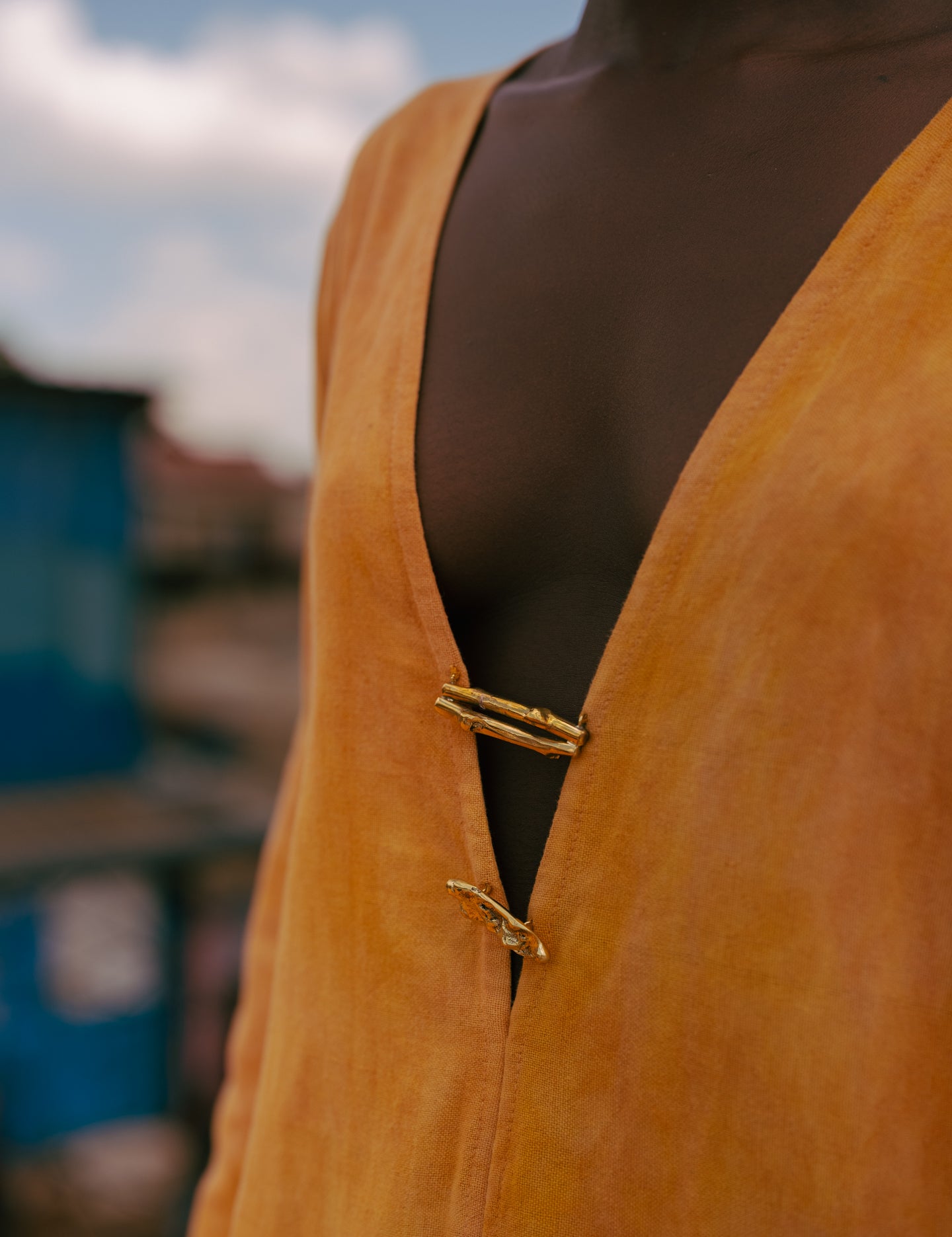 Artisan hand-cast brass hardware and turmeric-dyed cotton fabric on LilaBare kaftan tunic