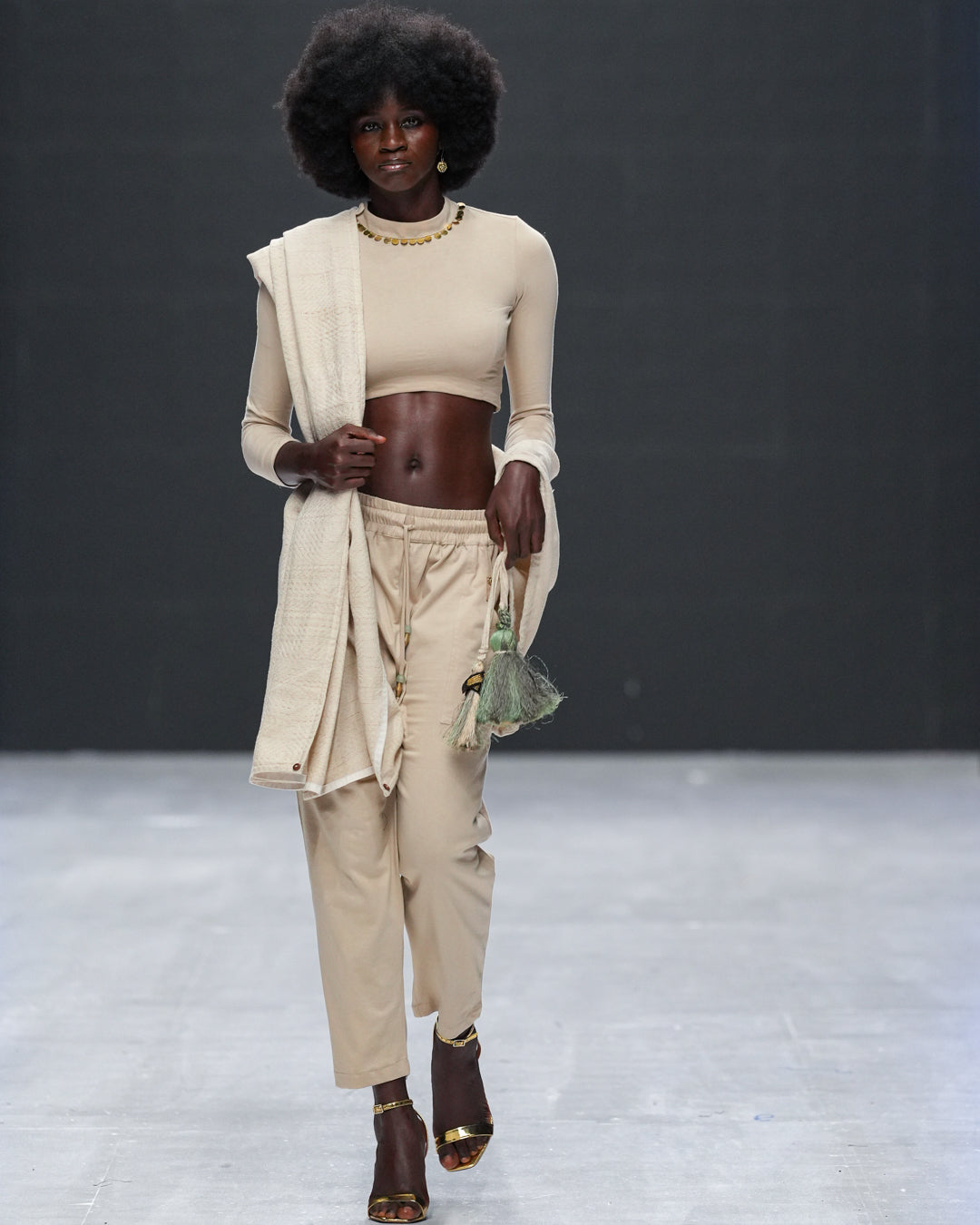 Front view of runway model wearing LilaBare’s Choker Crop Top with hand-applied brass sequin neckline layered with scarf