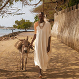 Model wearing LilaBare’s One Shoulder Sari Dress in undyed handloom cotton, walking barefoot in golden desert sand at sunrise.