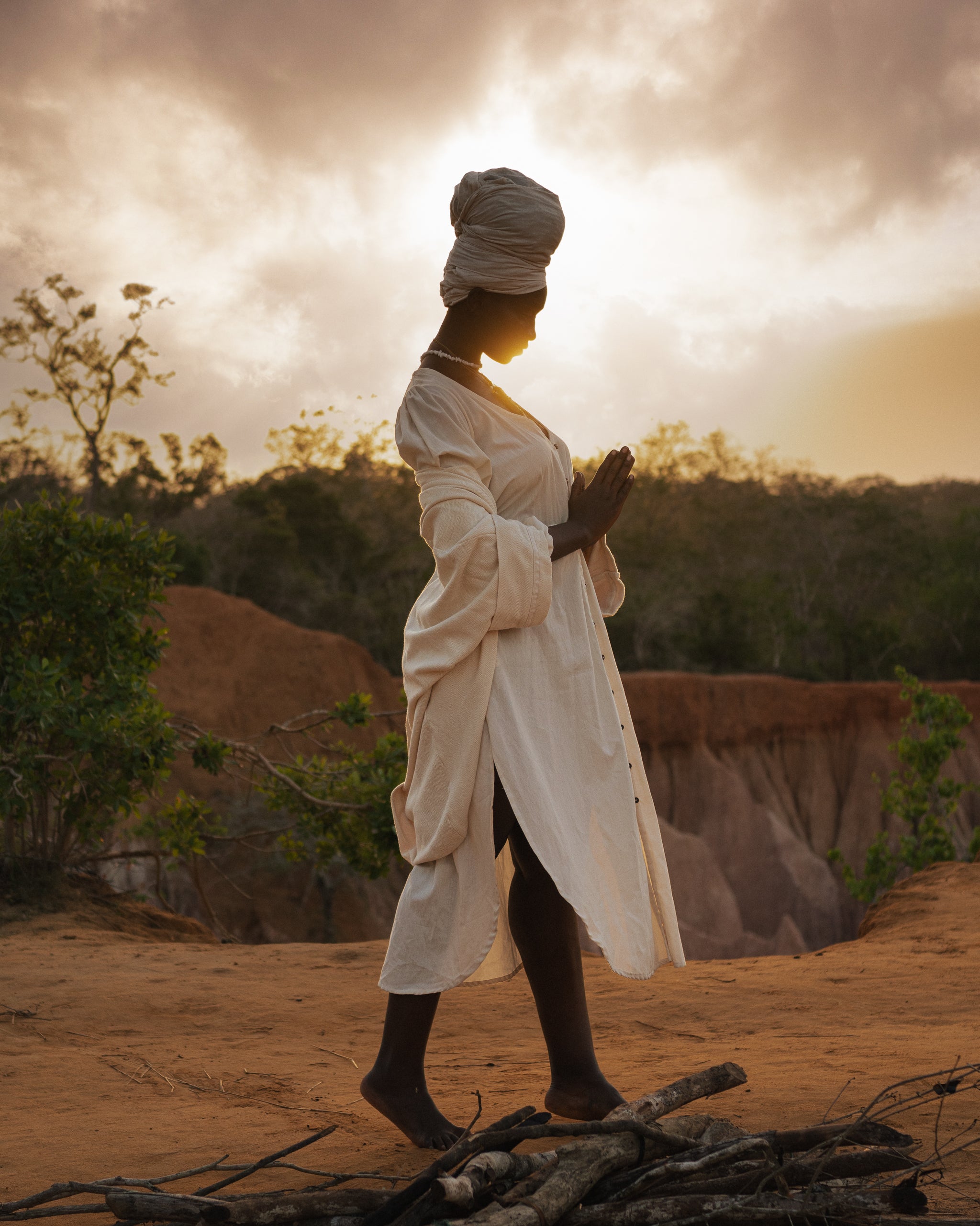 Woman walking barefoot in flowing LilaBare Louise Cape Dress made of handwoven cotton and turban