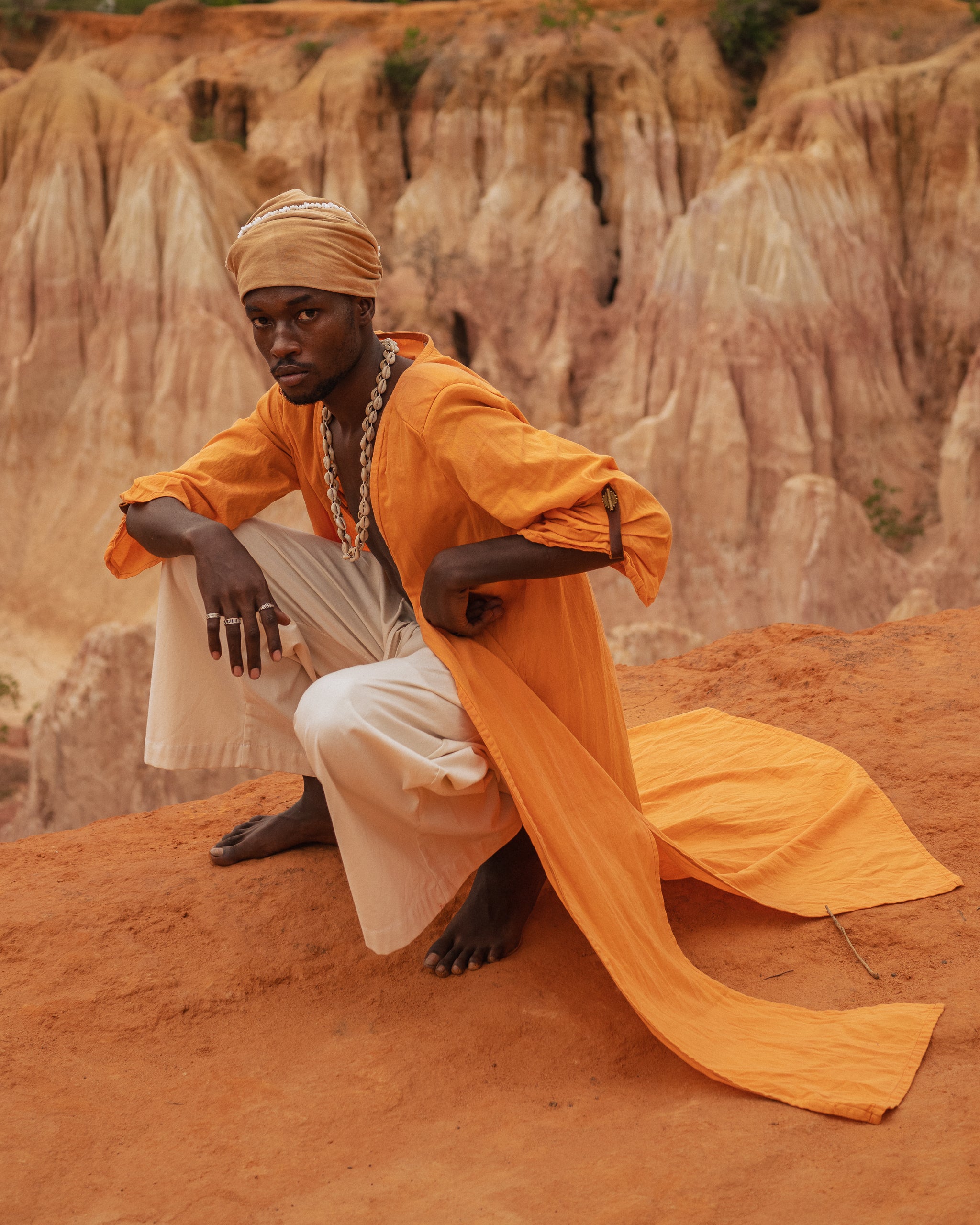 Model sitting cliffside wearing orange botanical-dyed long kimono
