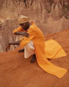 Model sitting cliffside wearing orange botanical-dyed long kimono