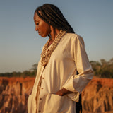 Model wears the Shakti Shirt and wide-leg pants in a sunlit natural setting, showcasing relaxed silhouette and gender-fluid style.