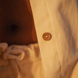 Close-up of LilaBare Shakti Shirt in natural cotton, showing natural button details and pockets.